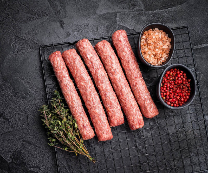 Cevapcici Fünf rohe Cevapcici aus feinem Rinderhack auf einem Teller